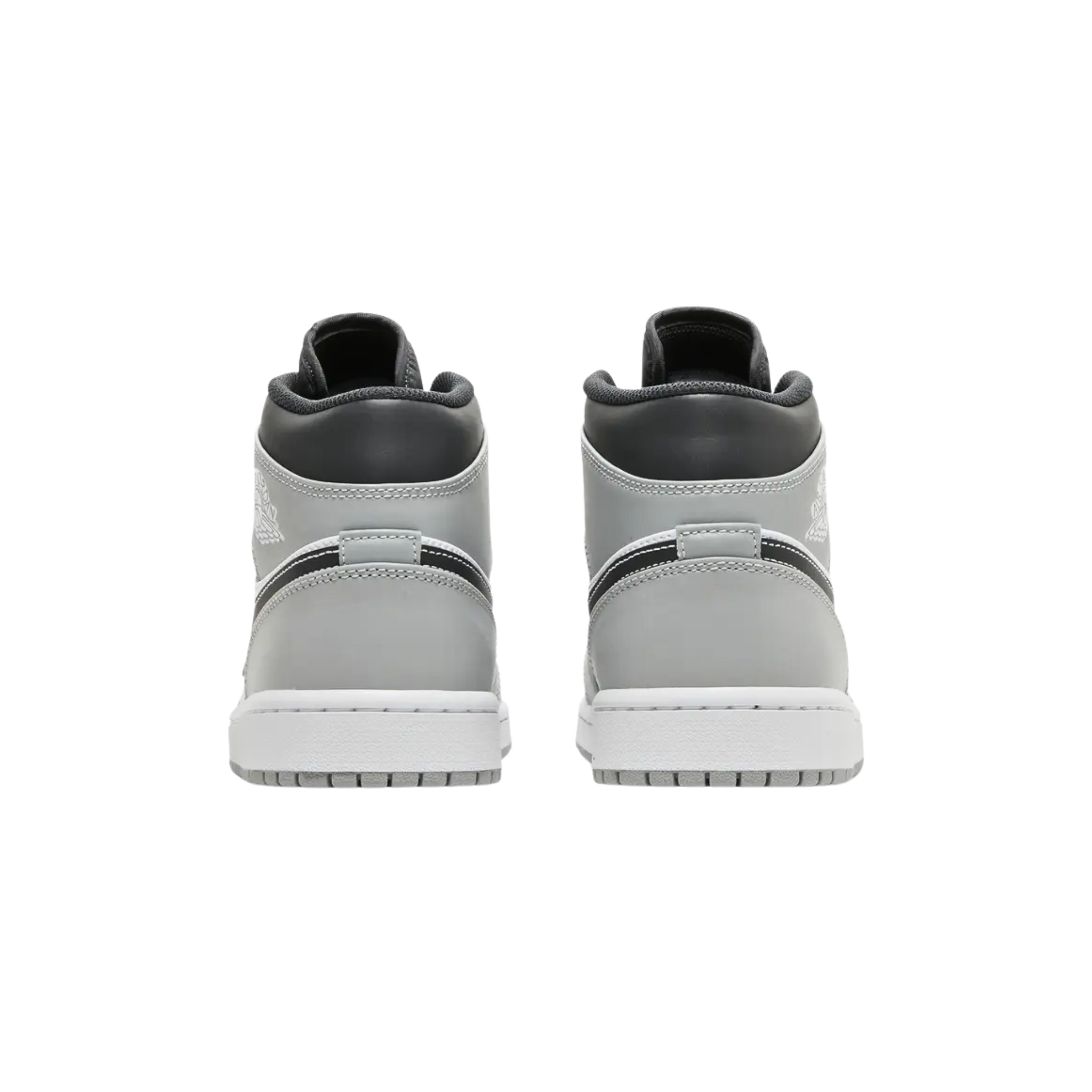 Air Jordan 1 Mid ‘Light Smoke Grey’ Anthracite featuring a smooth leather upper with a white base and light grey overlays at the forefoot and heel. The sneaker includes black accents on the mid-cut collar and Swoosh, with contrast white stitching. Additional branding includes a Jumpman icon on the woven tongue tag and a retro Wings logo on the lateral ankle. It is mounted on a durable rubber cupsole with an encapsulated Air-sole heel unit in lightweight polyurethane.